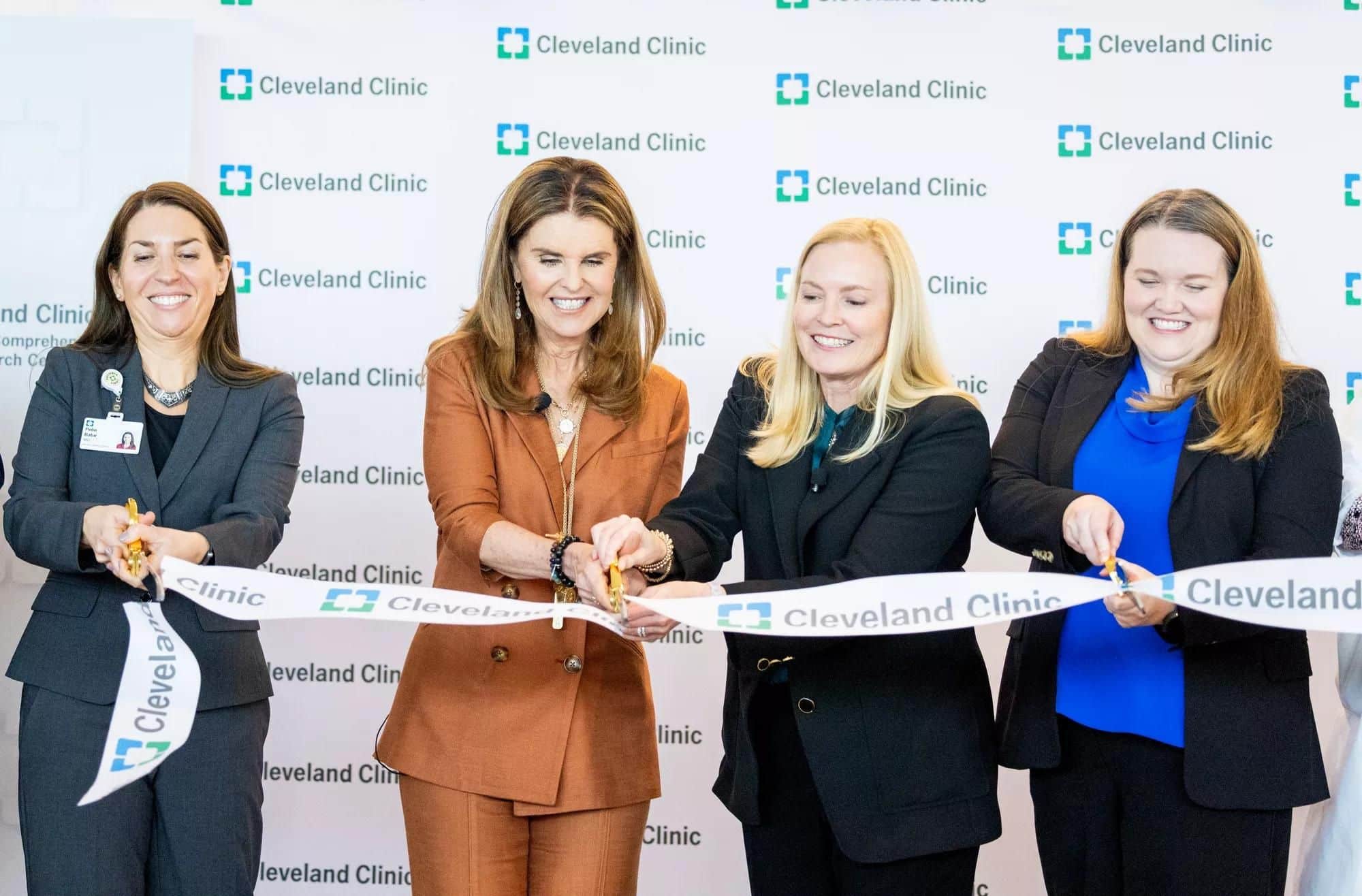 Maria Shriver & individuals at a ribbon-cutting ceremony with a Cleveland Clinic backdrop.