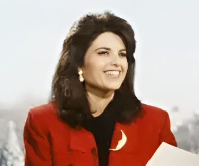 Maria Shriver in red coat reading a paper with a blurred background.